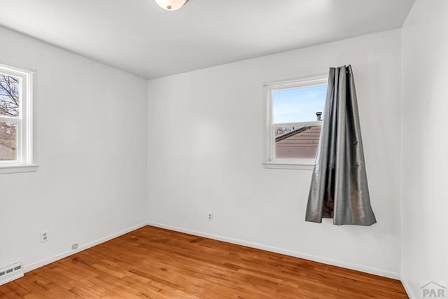 unfurnished room featuring light wood-type flooring, a baseboard heating unit, and baseboards