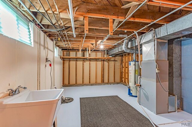 basement featuring a sink, heating unit, and water heater