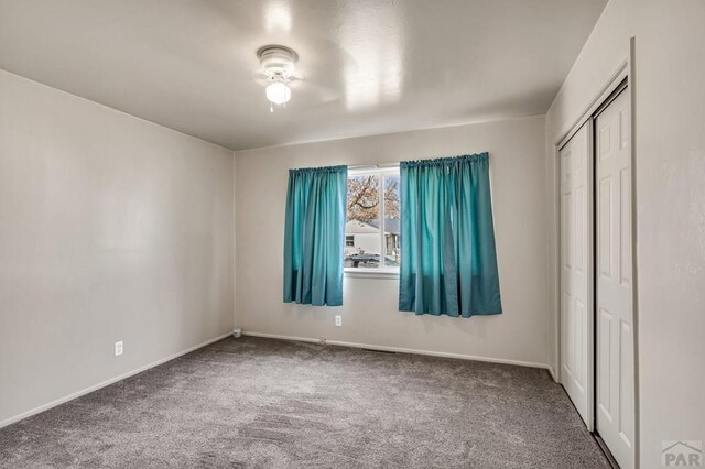 unfurnished bedroom featuring a closet, carpet flooring, ceiling fan, and baseboards