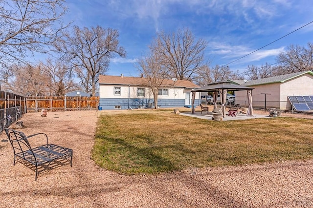 rear view of house with a gazebo, a patio area, a lawn, and a fenced backyard