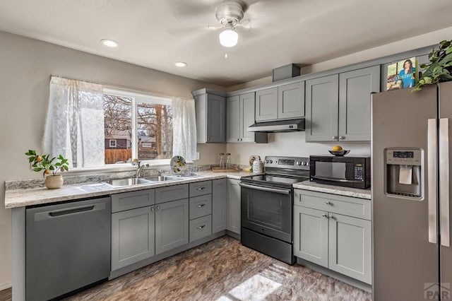 kitchen with under cabinet range hood, stainless steel appliances, gray cabinets, and a sink