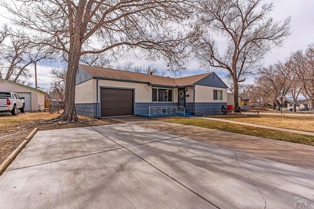 view of front of property featuring covered porch, driveway, a garage, and stucco siding