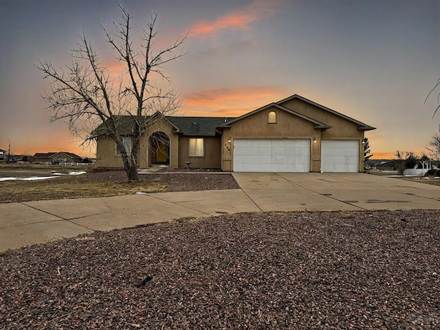 view of front facade featuring a garage, driveway, and stucco siding