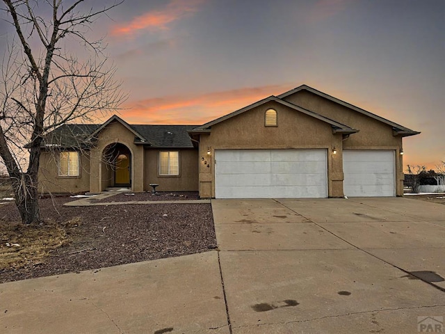 single story home with concrete driveway, an attached garage, and stucco siding