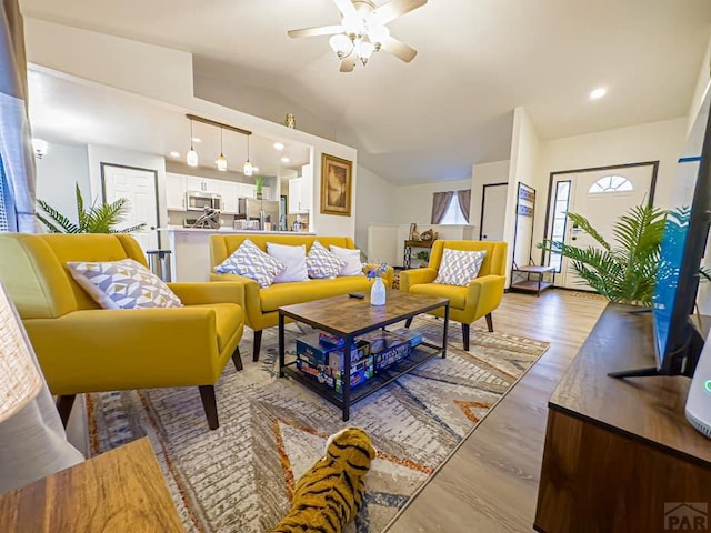 living area with lofted ceiling, light wood finished floors, and a ceiling fan