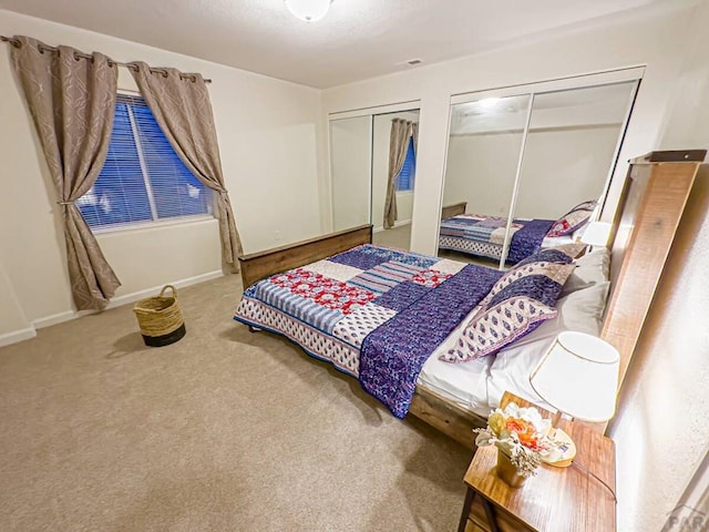 bedroom with carpet flooring, a textured ceiling, baseboards, and two closets