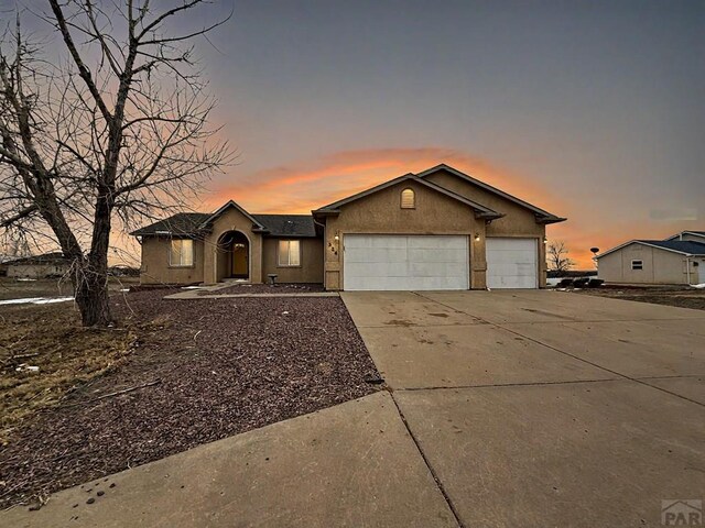 ranch-style home with a garage, concrete driveway, and stucco siding