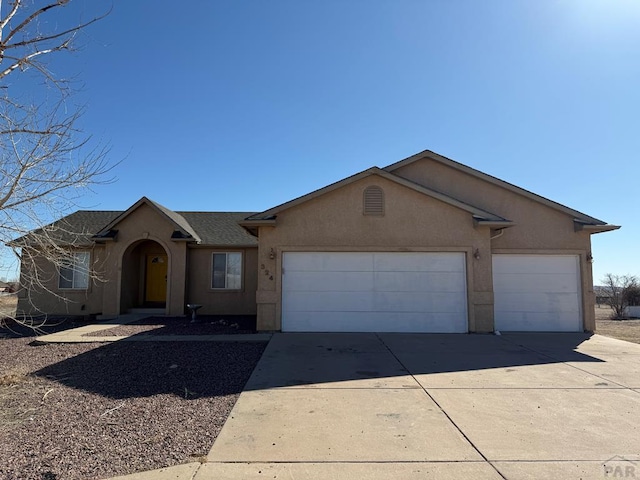 ranch-style house featuring a garage, concrete driveway, roof with shingles, and stucco siding