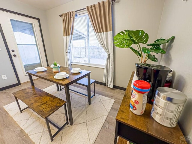 dining space featuring baseboards and light wood-style floors