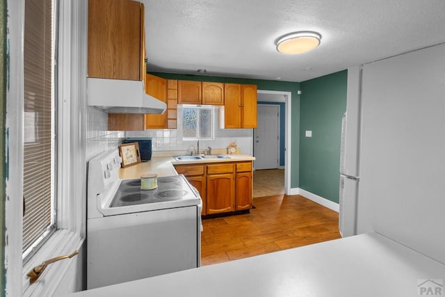 kitchen with under cabinet range hood, white electric range, a sink, light wood-style floors, and light countertops