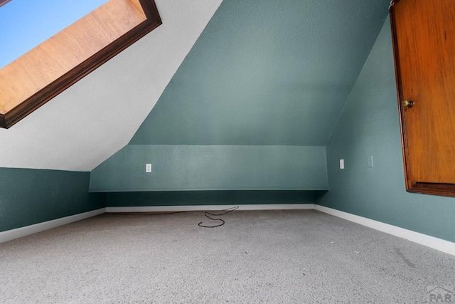 bonus room featuring lofted ceiling with skylight and baseboards