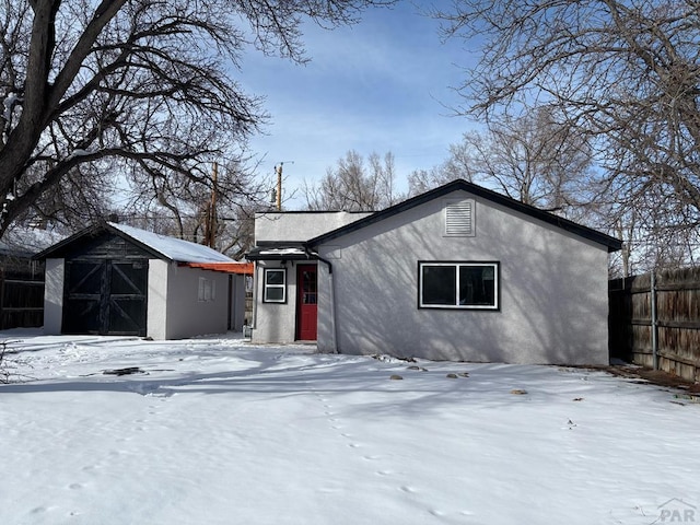 view of front of house with an outbuilding, fence, a shed, and stucco siding