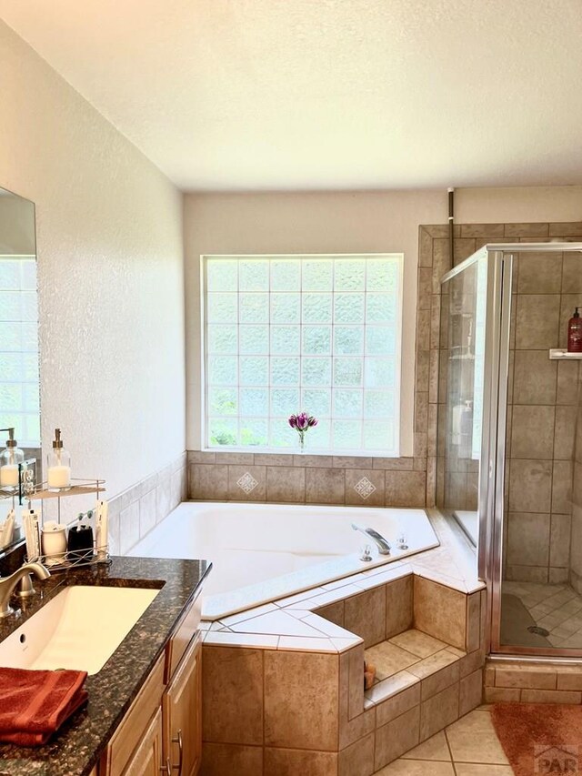 bathroom with a stall shower, a healthy amount of sunlight, vanity, and a bath