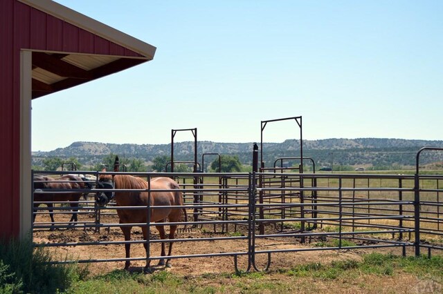 view of horse barn featuring a rural view and a mountain view