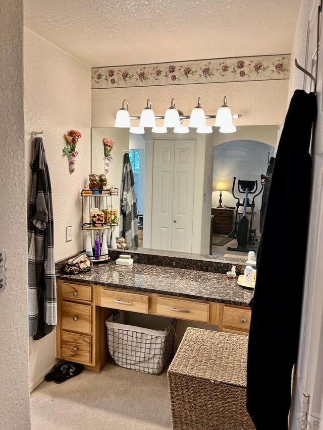 bathroom with a textured ceiling, a textured wall, a closet, and vanity