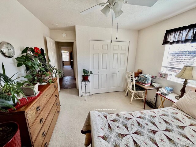 bedroom featuring a ceiling fan, a closet, light colored carpet, and a textured ceiling