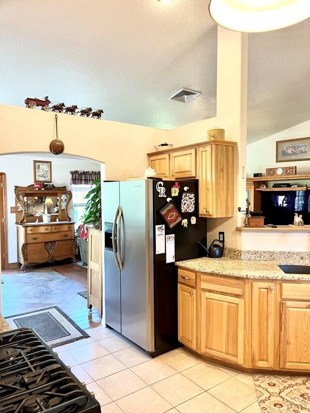 kitchen featuring visible vents, stainless steel refrigerator with ice dispenser, a textured ceiling, and light tile patterned flooring