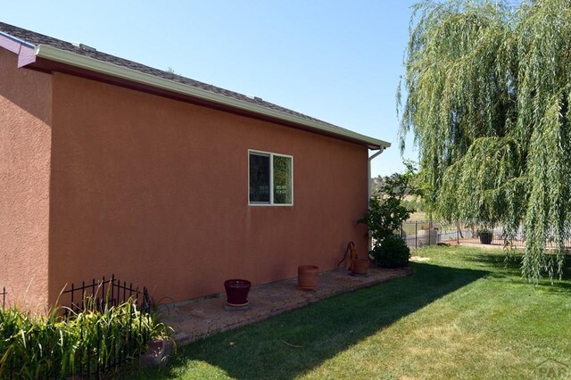 view of home's exterior with fence, a lawn, and stucco siding