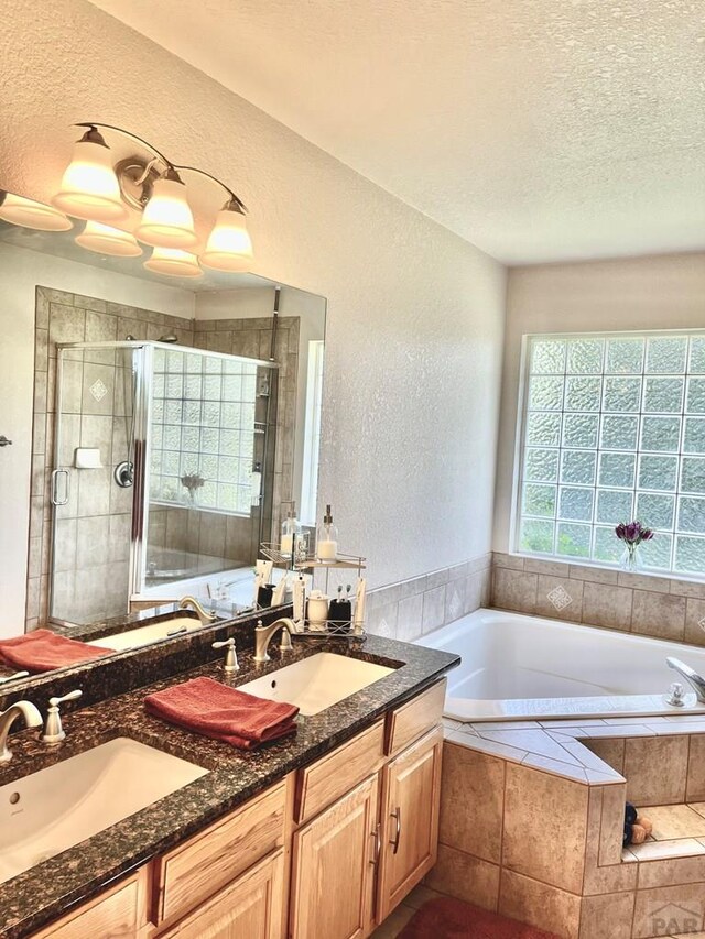 full bath with a stall shower, a sink, a textured ceiling, and double vanity