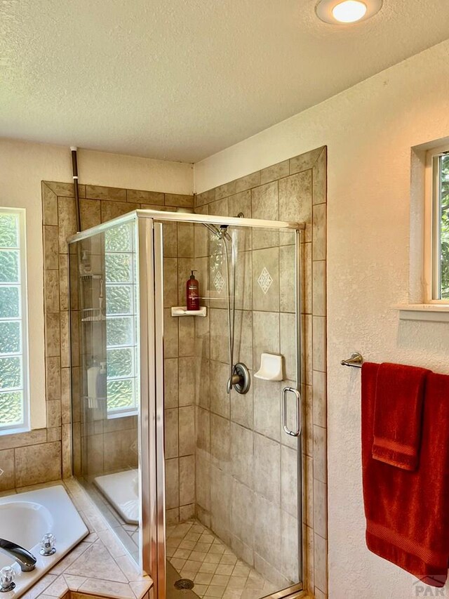 full bath with a garden tub, a textured wall, a shower stall, and a textured ceiling