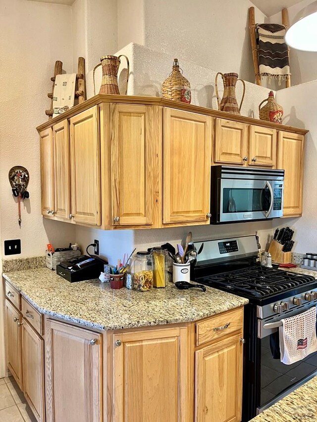 kitchen featuring stainless steel appliances, light tile patterned floors, and light stone countertops