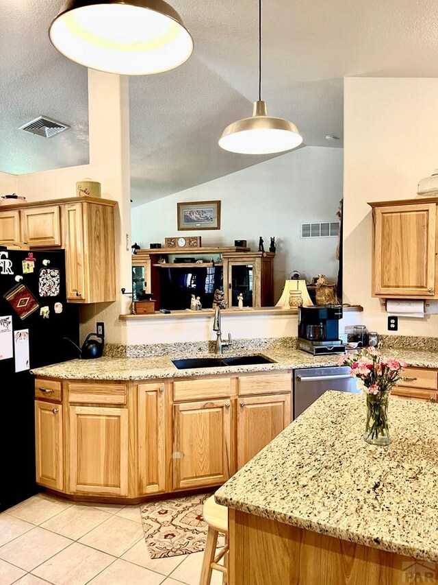 kitchen featuring visible vents, dishwasher, freestanding refrigerator, hanging light fixtures, and a sink