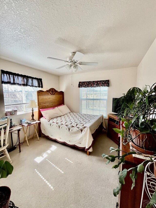 carpeted bedroom featuring a textured ceiling, multiple windows, and a ceiling fan