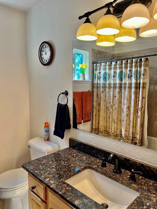 full bath featuring toilet, a textured wall, and vanity