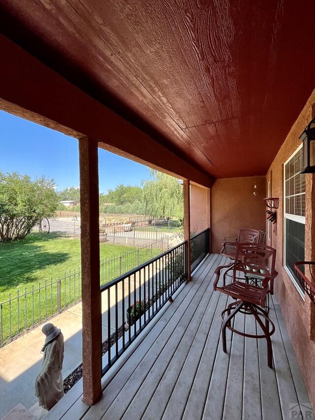 wooden terrace with a lawn and fence