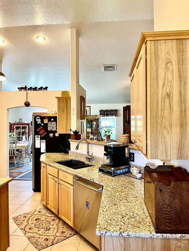 kitchen featuring light tile patterned floors, light stone counters, a peninsula, a sink, and dishwasher