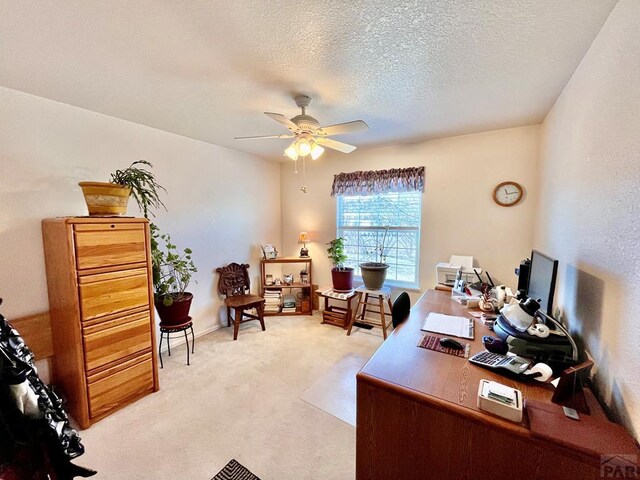 office featuring a textured ceiling, ceiling fan, and light colored carpet