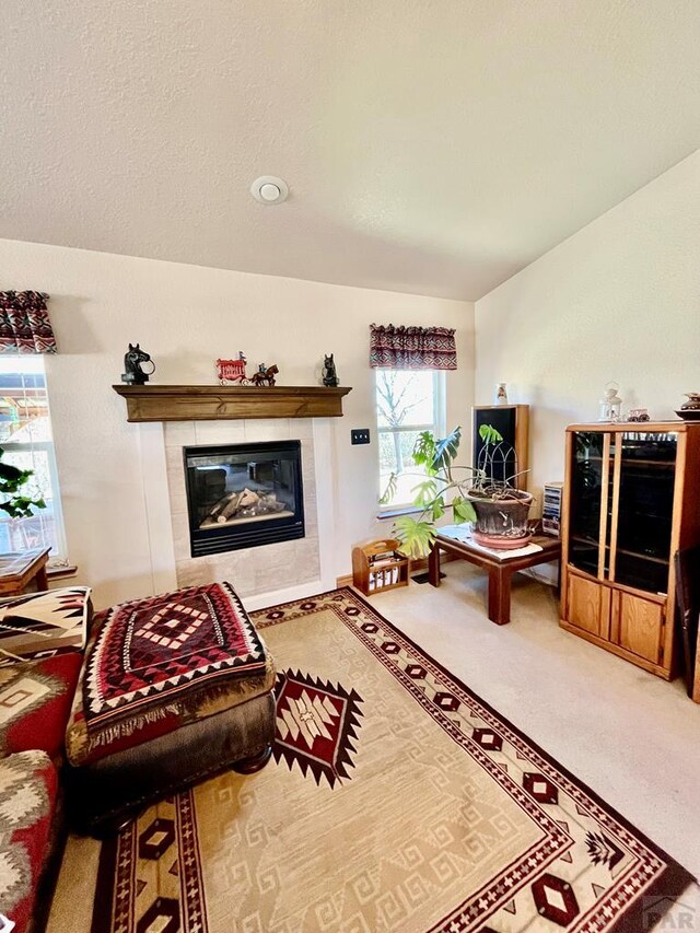 living area featuring a textured ceiling, carpet floors, and a tile fireplace