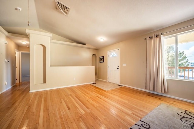 foyer with vaulted ceiling, light wood-style flooring, visible vents, and baseboards