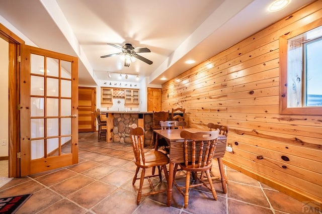 tiled dining space featuring wood walls, rail lighting, a ceiling fan, and recessed lighting