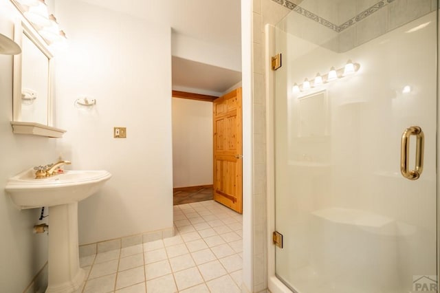 bathroom featuring baseboards, a sink, tile patterned flooring, and a shower stall