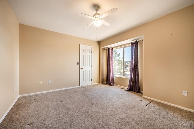 carpeted empty room with ceiling fan and baseboards