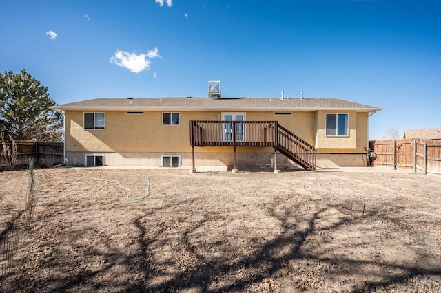 back of property with a deck, stairway, a fenced backyard, and stucco siding