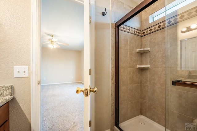 bathroom featuring a stall shower, a ceiling fan, and vanity