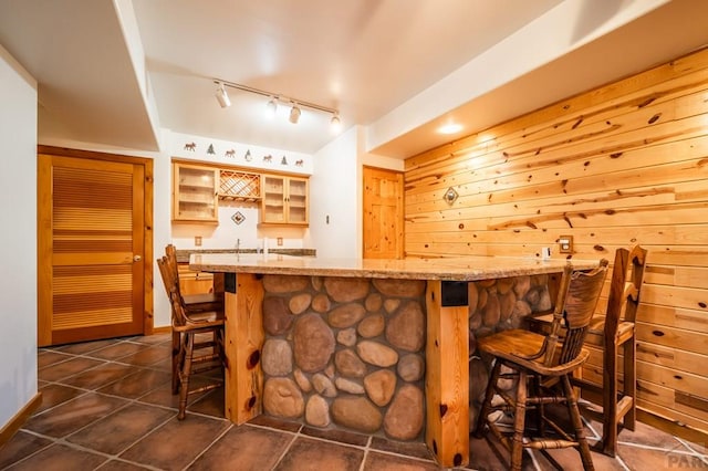 bar featuring rail lighting, dark tile patterned floors, and wet bar