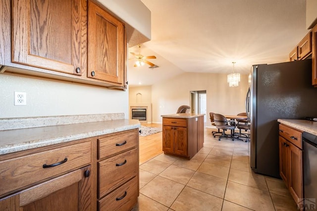 kitchen featuring brown cabinets, ceiling fan with notable chandelier, stainless steel appliances, and light tile patterned flooring