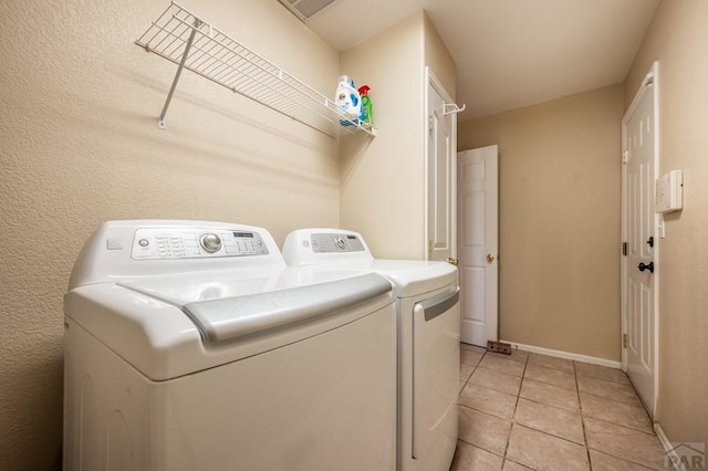 washroom featuring washer and dryer, laundry area, baseboards, and light tile patterned floors