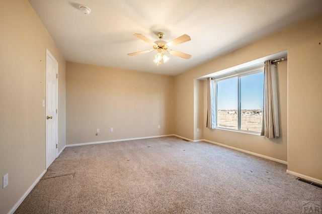 spare room with a ceiling fan, carpet flooring, visible vents, and baseboards