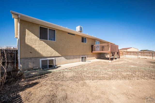 rear view of house with a deck, cooling unit, fence, stairs, and stucco siding