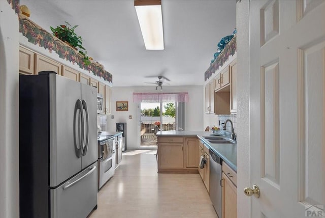 kitchen featuring light brown cabinets, a sink, a peninsula, stainless steel appliances, and light wood-style flooring