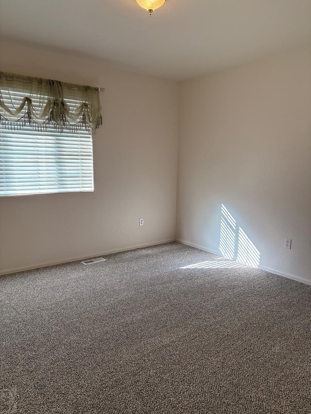 empty room featuring visible vents, baseboards, and carpet flooring