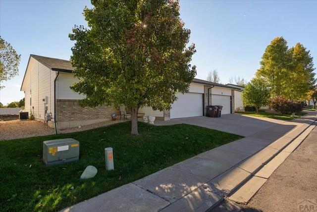 view of property hidden behind natural elements with concrete driveway and a front yard