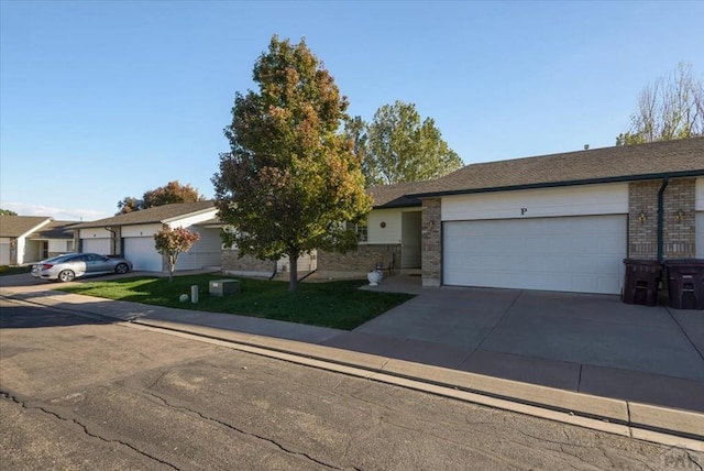 ranch-style house with a front yard, an attached garage, brick siding, and driveway