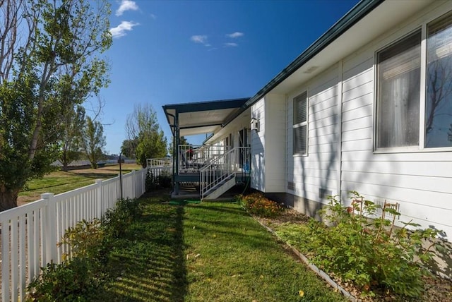 view of side of property featuring a yard, stairway, and fence