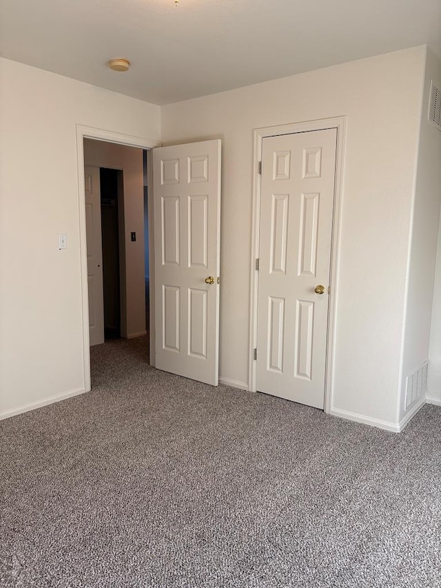 unfurnished bedroom featuring carpet, visible vents, and baseboards
