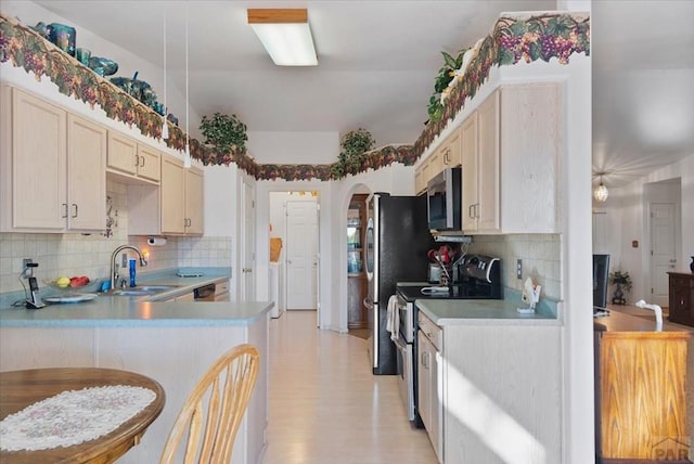 kitchen with light countertops, backsplash, appliances with stainless steel finishes, arched walkways, and a sink